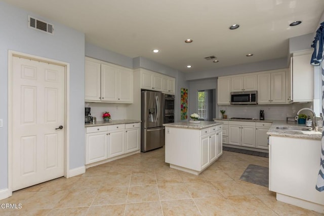 904 Calle Higuera, Camarillo, CA 93010 - kitchen featuring a sink, appliances with stainless steel finishes, a kitchen island, light stone countertops, and light tile patterned floors