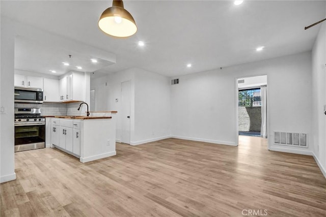 700 W 3rd St Unit A117, Santa Ana, CA 92701 - kitchen featuring appliances with stainless steel finishes, light wood-type flooring, decorative backsplash, recessed lighting, and white cabinets