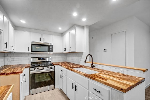 700 W 3rd St Unit A117, Santa Ana, CA 92701 - kitchen featuring wood counters, appliances with stainless steel finishes, a sink, a peninsula, and light wood-style floors