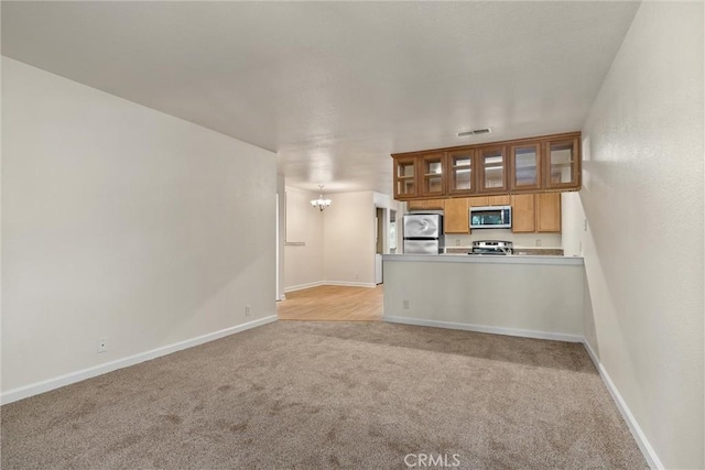 1114 Nord Ave Unit 36, Chico, CA 95926 - kitchen with stainless steel appliances, light colored carpet, a peninsula, glass insert cabinets, and baseboards