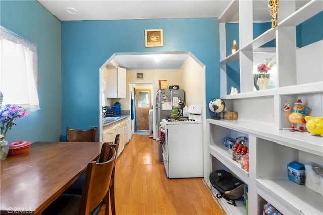 151 E 105th St, Los Angeles, CA 90003 - kitchen with white range with gas cooktop, arched walkways, light wood-style floors, a sink, and white cabinets