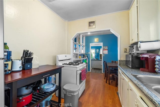 151 E 105th St, Los Angeles, CA 90003 - kitchen featuring gas range gas stove, light wood-style floors, a sink, ornamental molding, and cream cabinetry