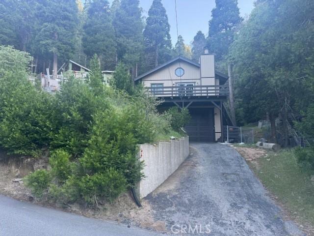 968 Lausanne Dr, Crestline, CA 92325 - view of front of home featuring driveway, an attached garage, a chimney, and a deck