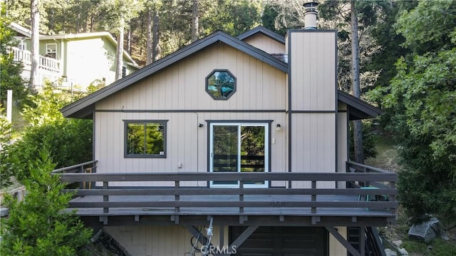 968 Lausanne Dr, Crestline, CA 92325 - back of property with a chimney, a deck, and view of wooded area