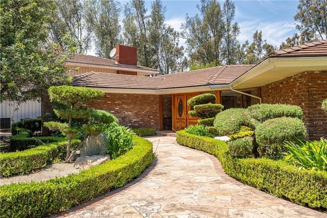 20827 E Mesarica Rd, Covina, CA 91724 - view of front of house featuring a tile roof, brick siding, a chimney, and cooling unit