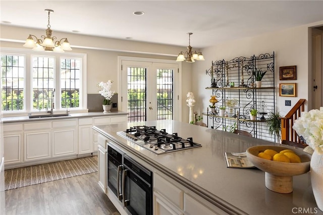 11 La Linda Dr, Long Beach, CA 90807 - kitchen featuring a chandelier, stainless steel gas cooktop, a sink, white cabinets, and decorative light fixtures