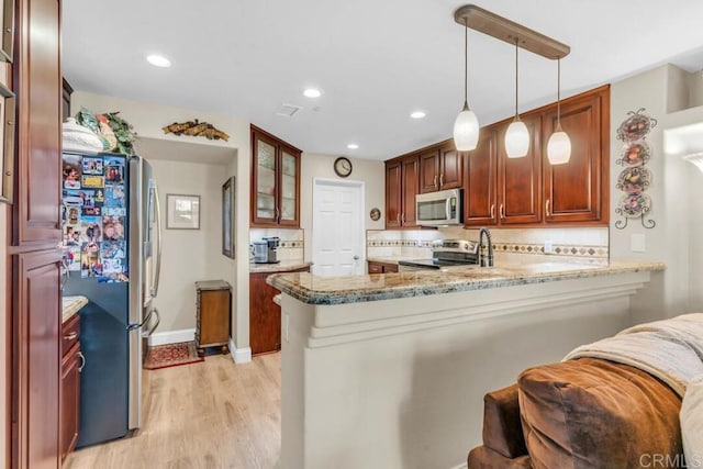 1873 Key Largo Rd, Vista, CA 92081 - kitchen with stainless steel appliances, a peninsula, light wood-type flooring, light stone countertops, and glass insert cabinets