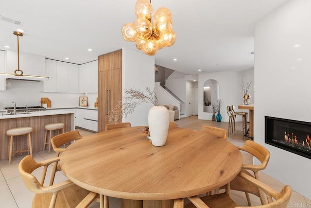 16863 Abundante St, San Diego, CA 92127 - dining area featuring stairway, arched walkways, a glass covered fireplace, light tile patterned floors, and a chandelier