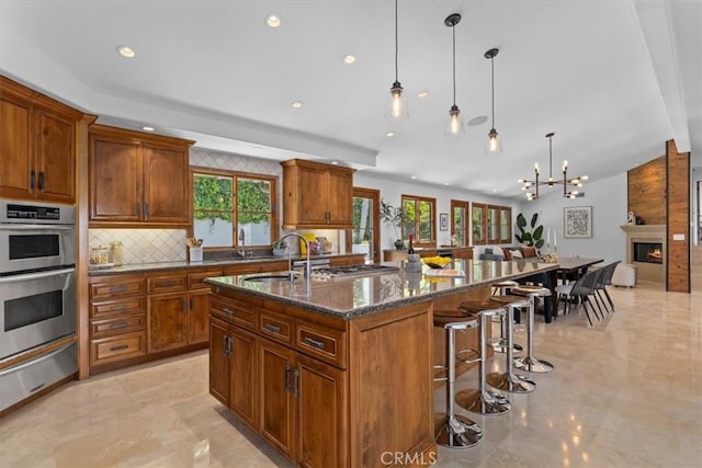 364 Via Almar, Palos Verdes Estates, CA 90274 - kitchen with stainless steel double oven, a warming drawer, brown cabinetry, backsplash, and an island with sink