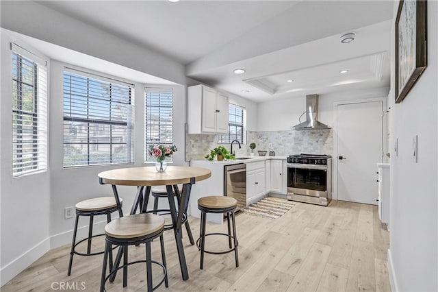 2633 Monte Carlo Unit 41, Santa Ana, CA 92706 - kitchen with stainless steel appliances, wall chimney exhaust hood, tasteful backsplash, light wood-style floors, and light countertops