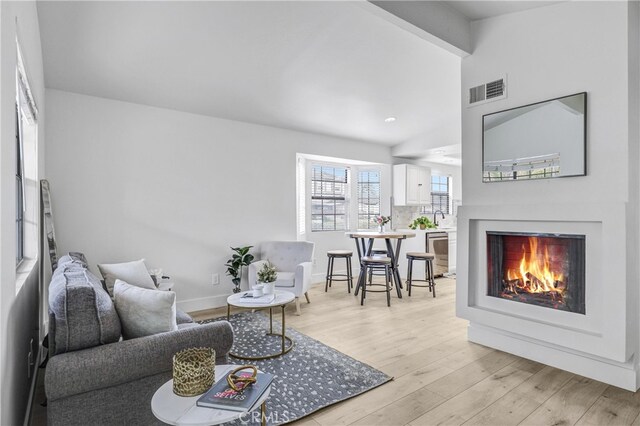 2633 Monte Carlo Unit 41, Santa Ana, CA 92706 - living area with a lit fireplace, light wood-style flooring, lofted ceiling, and baseboards