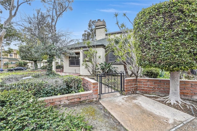 2633 Monte Carlo Unit 41, Santa Ana, CA 92706 - view of front of home featuring stucco siding, a fenced front yard, a chimney, and a gate