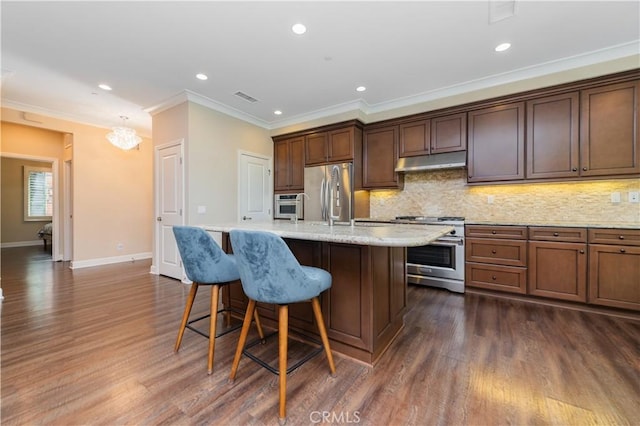 43 Lupari, Irvine, CA 92618 - kitchen with appliances with stainless steel finishes, under cabinet range hood, crown molding, tasteful backsplash, and a center island with sink