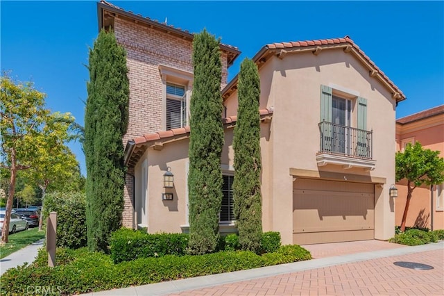 43 Lupari, Irvine, CA 92618 - view of front of home with a balcony, a tiled roof, brick siding, an attached garage, and stucco siding