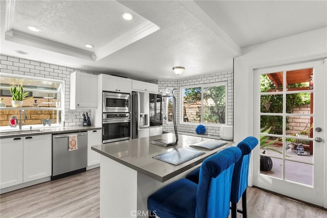 19777 Azure Field Dr, Newhall, CA 91321 - kitchen featuring appliances with stainless steel finishes, a sink, a textured ceiling, light wood-style floors, and white cabinetry