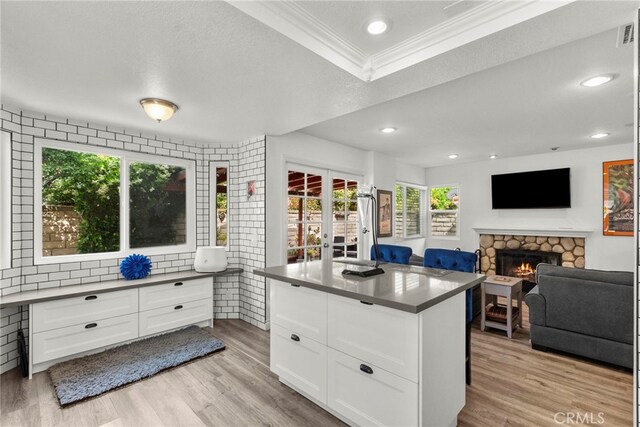 19777 Azure Field Dr, Newhall, CA 91321 - kitchen with crown molding, healthy amount of natural light, a fireplace, white cabinetry, and light wood-style flooring