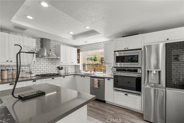 19777 Azure Field Dr, Newhall, CA 91321 - kitchen featuring appliances with stainless steel finishes, a raised ceiling, wall chimney exhaust hood, dark countertops, and a textured ceiling