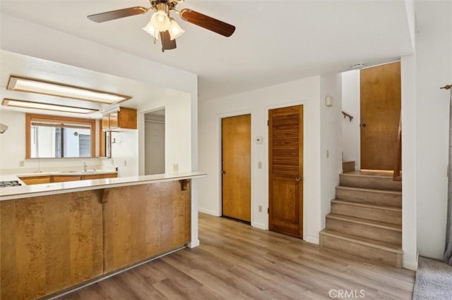 10710 El Camino Real Unit 17, Atascadero, CA 93422 - kitchen with ceiling fan, a sink, light wood-style flooring, light countertops, and a peninsula