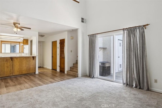 10710 El Camino Real Unit 17, Atascadero, CA 93422 - unfurnished living room with ceiling fan, carpet flooring, stairway, baseboards, and a high ceiling