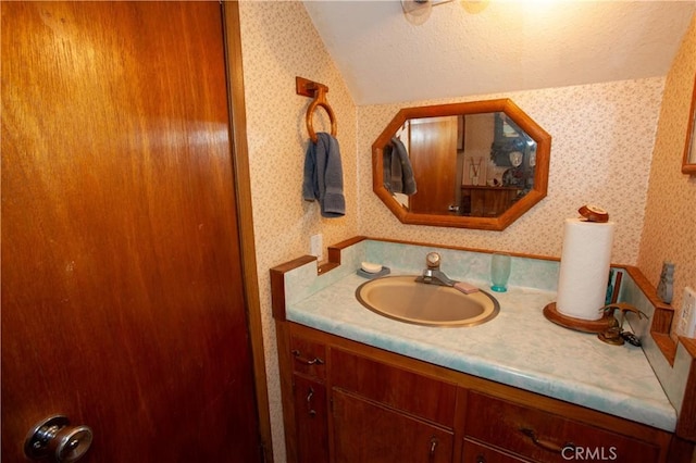 31510 Overhill Dr, Running Springs, CA 92382 - bathroom with wallpapered walls, lofted ceiling, vanity, and a textured ceiling