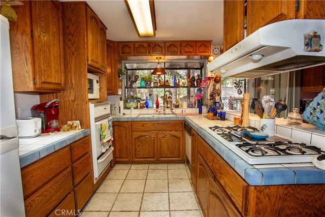 31510 Overhill Dr, Running Springs, CA 92382 - kitchen with white appliances, tile counters, under cabinet range hood, and brown cabinets