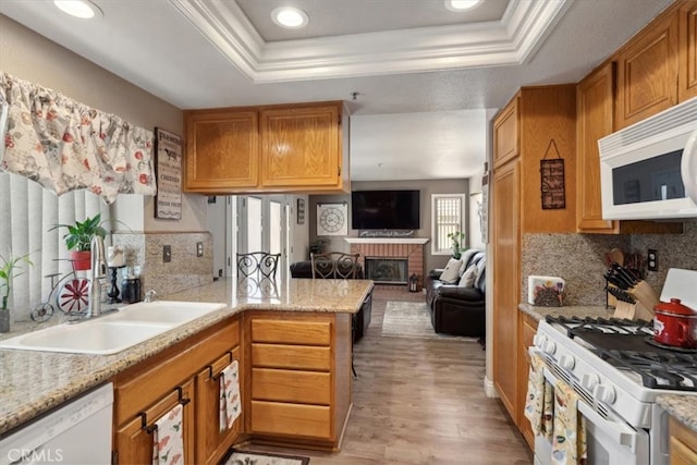 29159 Palm View Ln, Highland, CA 92346 - kitchen with white appliances, a tray ceiling, a peninsula, crown molding, and light wood finished floors