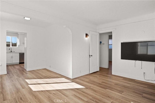 26021 President Ave, Harbor City, CA 90710 - unfurnished living room featuring a sink, light wood-type flooring, arched walkways, and baseboards