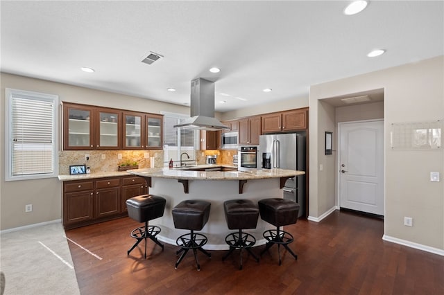 23650 Kathryn St, Murrieta, CA 92562 - kitchen featuring island exhaust hood, stainless steel appliances, a sink, a kitchen bar, and tasteful backsplash