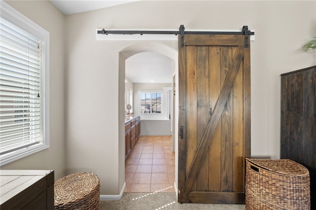 23650 Kathryn St, Murrieta, CA 92562 - corridor featuring a barn door, light tile patterned floors, arched walkways, and baseboards