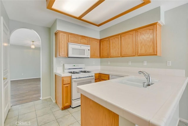 11241 Pleasant Hills Dr, Apple Valley, CA 92308 - kitchen with white appliances, a peninsula, a sink, light tile patterned floors, and arched walkways