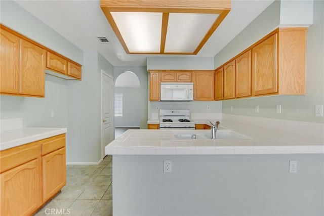 11241 Pleasant Hills Dr, Apple Valley, CA 92308 - kitchen with white appliances, a sink, a peninsula, light tile patterned flooring, and arched walkways