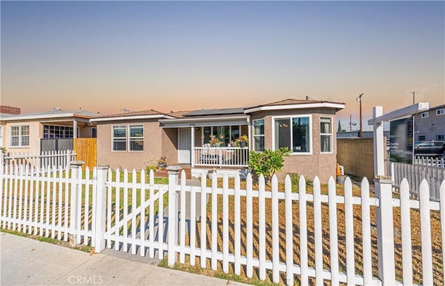 1915 E 55th St, Long Beach, CA 90805 - view of front facade with solar panels, stucco siding, a fenced front yard, and a porch