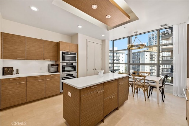 10776 Wilshire Blvd Unit 901, Los Angeles, CA 90024 - kitchen featuring brown cabinetry, light countertops, stainless steel double oven, a tray ceiling, and recessed lighting