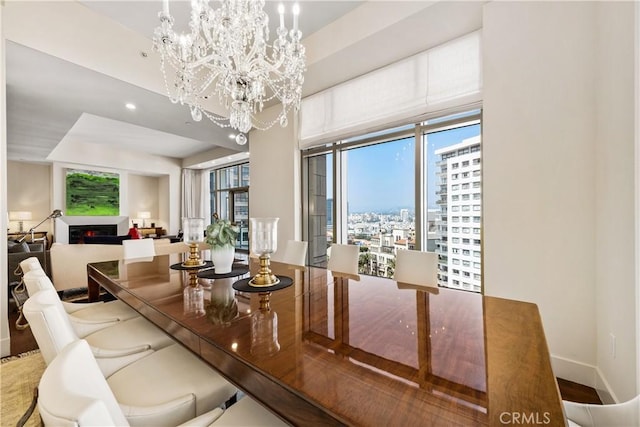 10776 Wilshire Blvd Unit 901, Los Angeles, CA 90024 - dining area with a chandelier, a lit fireplace, a city view, and baseboards