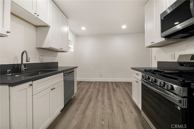 178 E Washington Ave, Chico, CA 95926 - kitchen with stainless steel appliances, a sink, baseboards, light wood-style flooring, and white cabinets