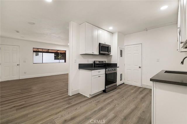 178 E Washington Ave, Chico, CA 95926 - kitchen with appliances with stainless steel finishes, dark countertops, wood finished floors, white cabinetry, and recessed lighting