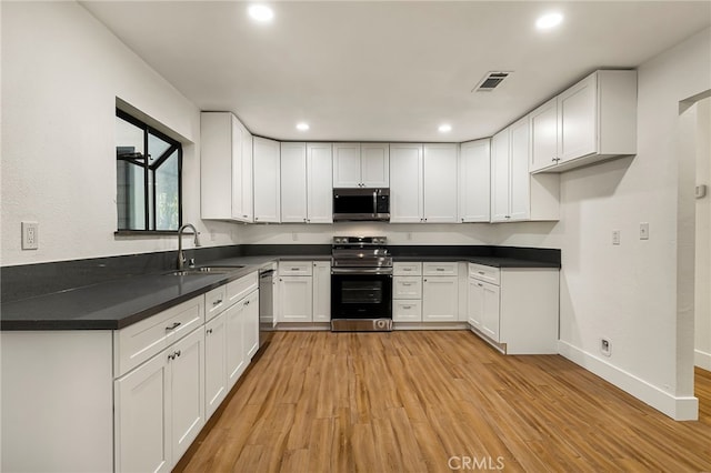 178 E Washington Ave, Chico, CA 95926 - kitchen with stainless steel appliances, a sink, light wood-style flooring, white cabinets, and recessed lighting