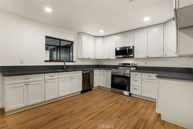 178 E Washington Ave, Chico, CA 95926 - kitchen with stainless steel appliances, a sink, light wood-type flooring, dark countertops, and white cabinetry
