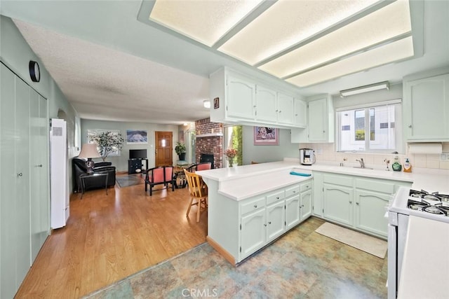 243 N 11th St, Grover Beach, CA 93433 - kitchen featuring healthy amount of natural light, a peninsula, a brick fireplace, open floor plan, and a textured ceiling