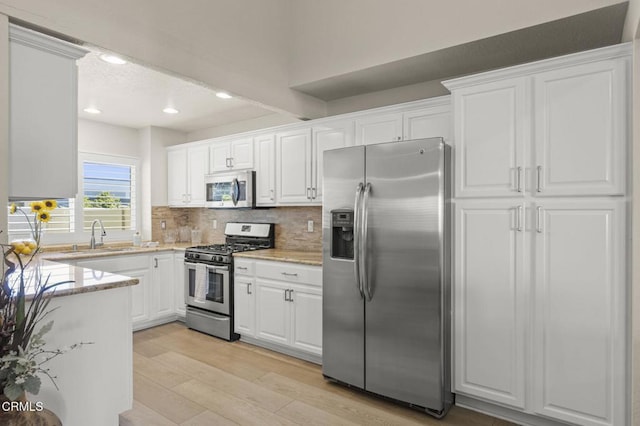 2036 Birchdale Ct, Thousand Oaks, CA 91362 - kitchen with stainless steel appliances, a sink, light wood finished floors, tasteful backsplash, and white cabinets
