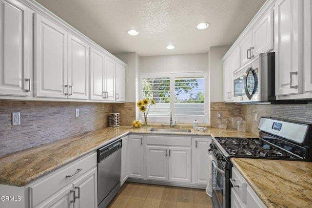 2036 Birchdale Ct, Thousand Oaks, CA 91362 - kitchen featuring appliances with stainless steel finishes, a sink, white cabinets, light wood-style floors, and decorative backsplash