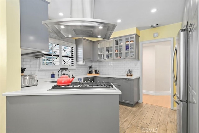 22941 Keswick St, West Hills, CA 91304 - kitchen featuring gray cabinetry, island range hood, appliances with stainless steel finishes, light wood-style floors, and backsplash