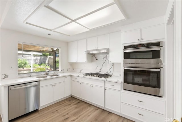 21965 Jeffers Ln, Saugus, CA 91350 - kitchen with stainless steel appliances, a sink, white cabinetry, under cabinet range hood, and light wood finished floors