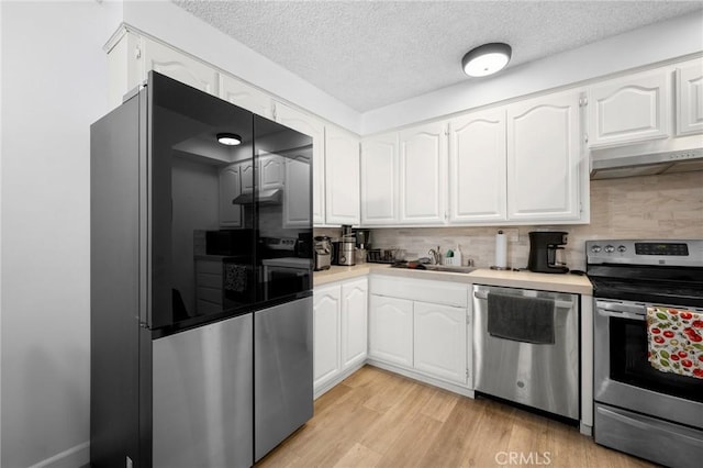 11025 Kittridge St Unit 128, North Hollywood, CA 91606 - kitchen featuring stainless steel appliances, under cabinet range hood, a sink, decorative backsplash, and white cabinets