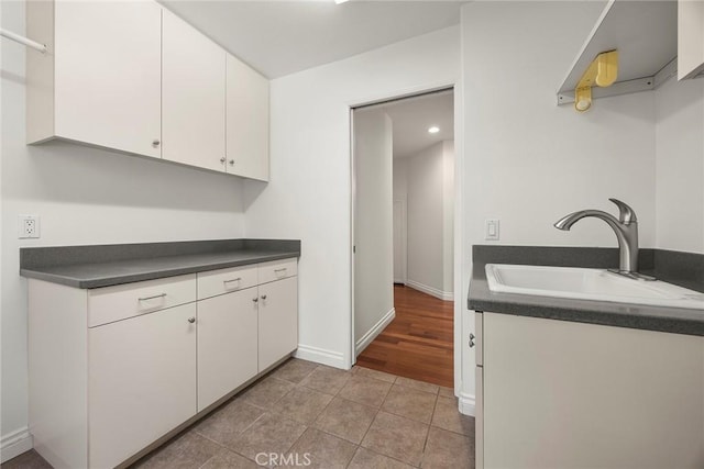 21 Mykonos, Laguna Niguel, CA 92677 - kitchen featuring a sink, dark countertops, white cabinets, light tile patterned floors, and baseboards