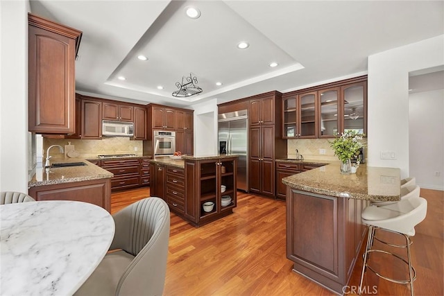 21 Mykonos, Laguna Niguel, CA 92677 - kitchen featuring appliances with stainless steel finishes, a raised ceiling, recessed lighting, a peninsula, and light wood-type flooring