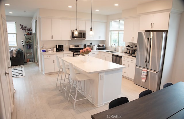 15941 Bravery Ave, Chino, CA 91708 - kitchen featuring appliances with stainless steel finishes, a kitchen breakfast bar, a center island, a sink, and pendant lighting