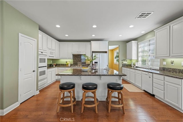 26520 Thackery Ln, Stevenson Ranch, CA 91381 - kitchen with white appliances, a center island, a kitchen breakfast bar, a warming drawer, and dark wood-style floors