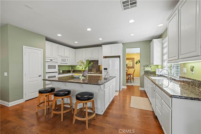 26520 Thackery Ln, Stevenson Ranch, CA 91381 - kitchen featuring white appliances, dark wood-type flooring, a kitchen island, recessed lighting, and a breakfast bar