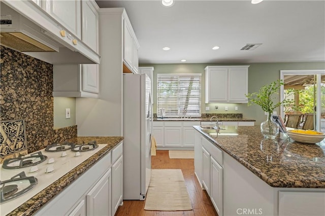26520 Thackery Ln, Stevenson Ranch, CA 91381 - kitchen with under cabinet range hood, white appliances, plenty of natural light, white cabinets, and recessed lighting